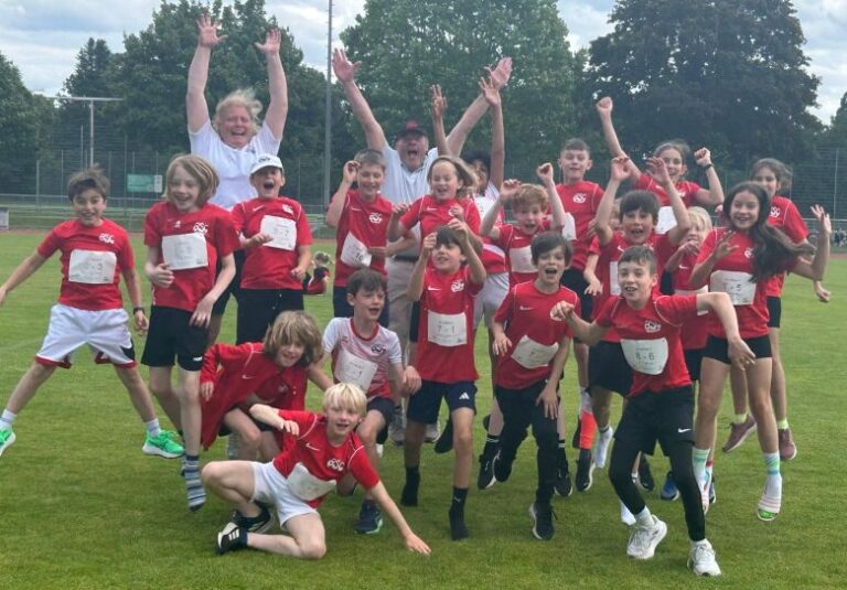 Kinder der Kinderleichtathletik des asc Darmstadt jubeln im roten Vereinstrikot auf dem Rasen