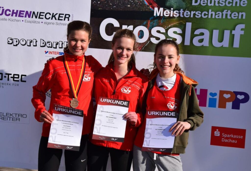Drei junge Athletinnen in roten asc-Trikots mit ihren Urkunden bei den Deutschen Crosslauf-Meisterschaften.